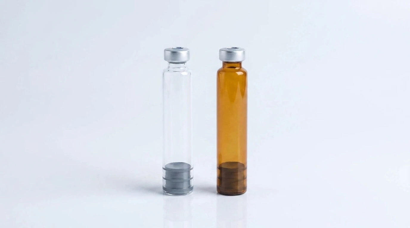Clear and amber 3 ml glass pen cartridges standing side by side on a studio background
