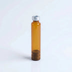 Amber borosilicate 3 ml glass pen cartridge standing upright: silver crimp cap with center septum on top, rubber plunger seated inside the amber glass at the base