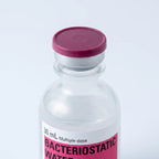Macro of the vial's sealed maroon flip-top cap on its aluminum crimp collar