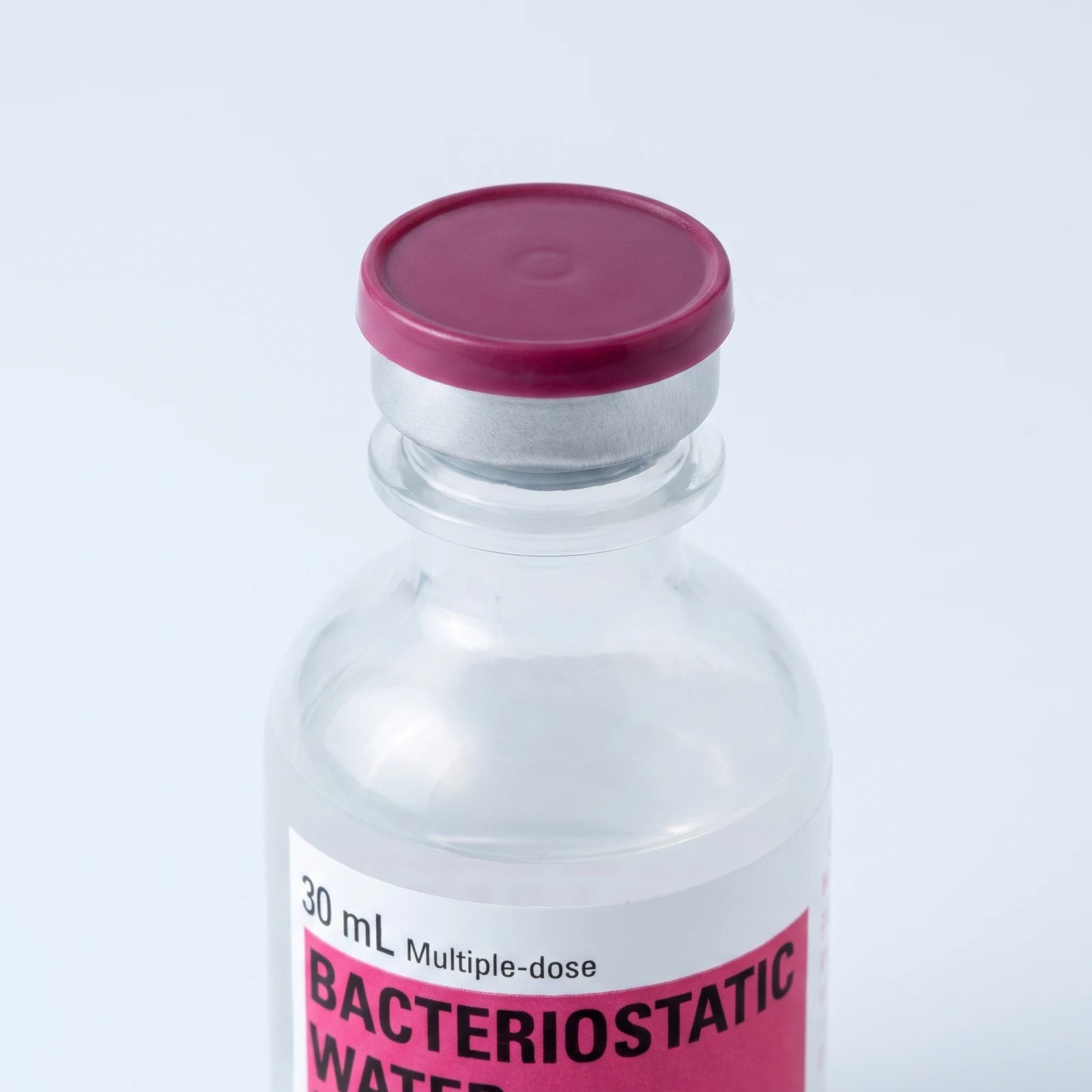 Macro of the vial's sealed maroon flip-top cap on its aluminum crimp collar