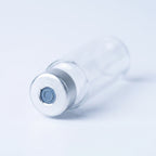 Macro of the cartridge's silver crimped aluminum cap: punched-open center exposing the blue-gray rubber septum disc