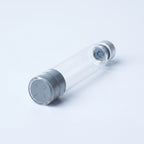 Standard 3 ml glass pen cartridge lying at a diagonal: flat gray rubber plunger face flush in the open glass end, silver crimped cap with exposed septum at the far end