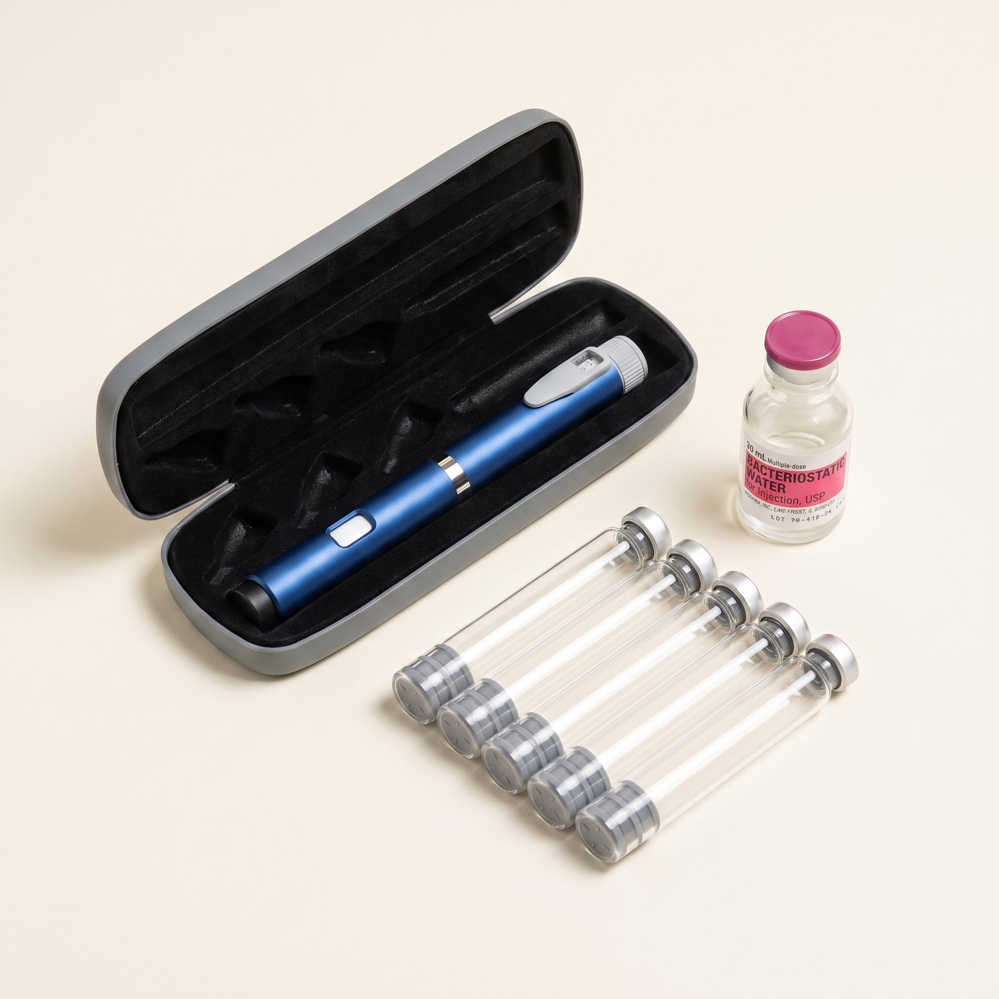 Starter kit laid out: a blue pen in its open grey case, five empty glass cartridges and a vial of bacteriostatic water