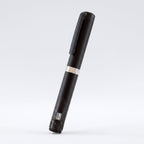 Matte black V3 Peptide Pen, reusable aluminium click-dial pen, angled diagonally on a pale studio background