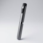 Gunmetal V2 Peptide Pen, reusable 60-unit pen with needle shield, angled diagonally on a pale studio background