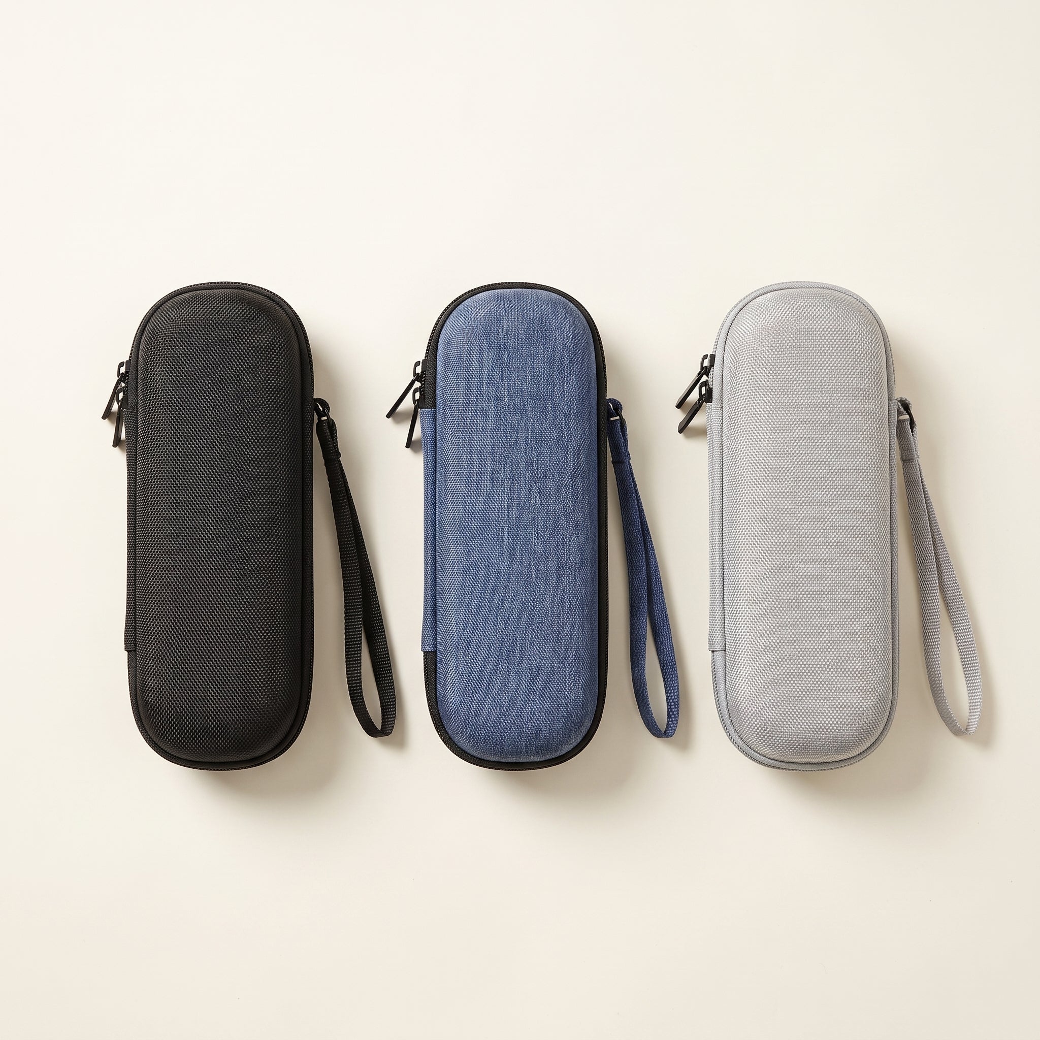 Three EVA travel cases side by side in black, denim blue and light grey, each with a wrist strap