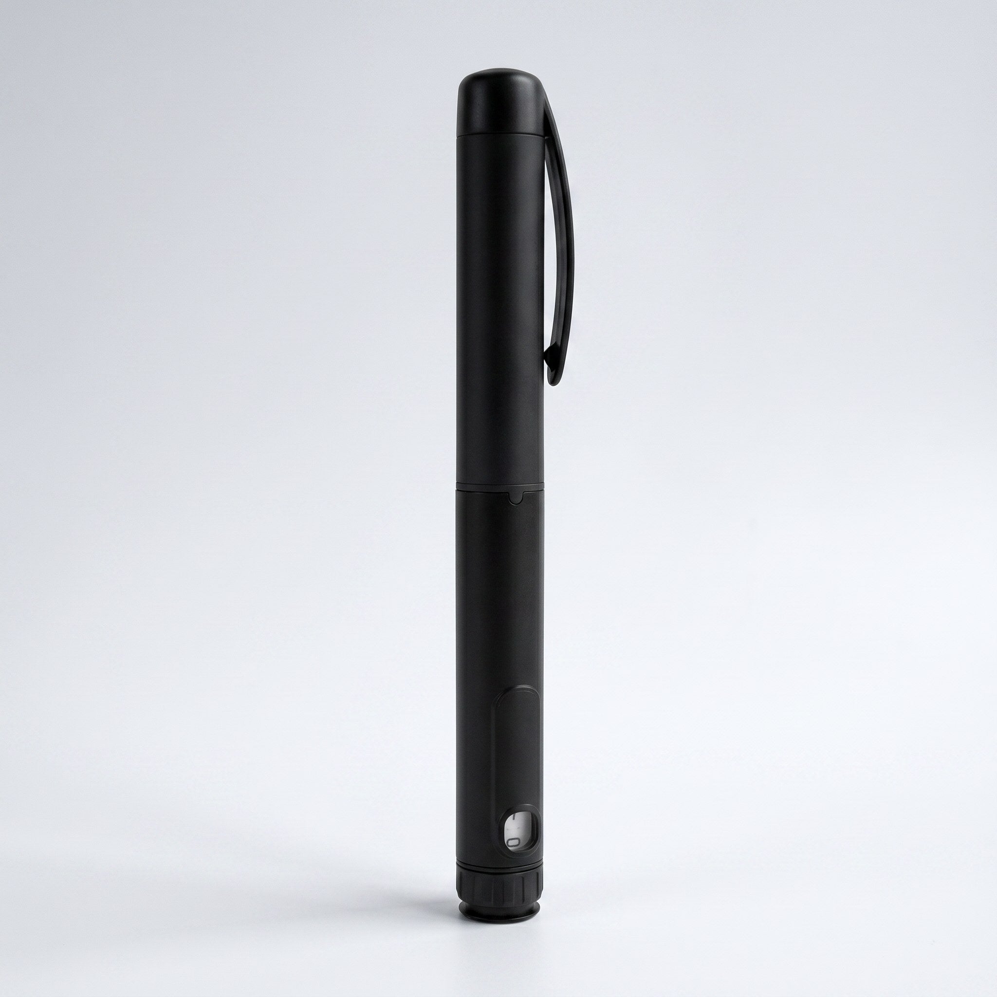 Matte black V1 Peptide Pen, reusable manual click-dial pen, standing upright on a pale studio background