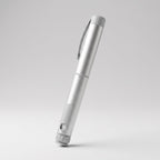 Brushed silver V1 Peptide Pen, reusable manual click-dial pen, angled diagonally on a pale studio background